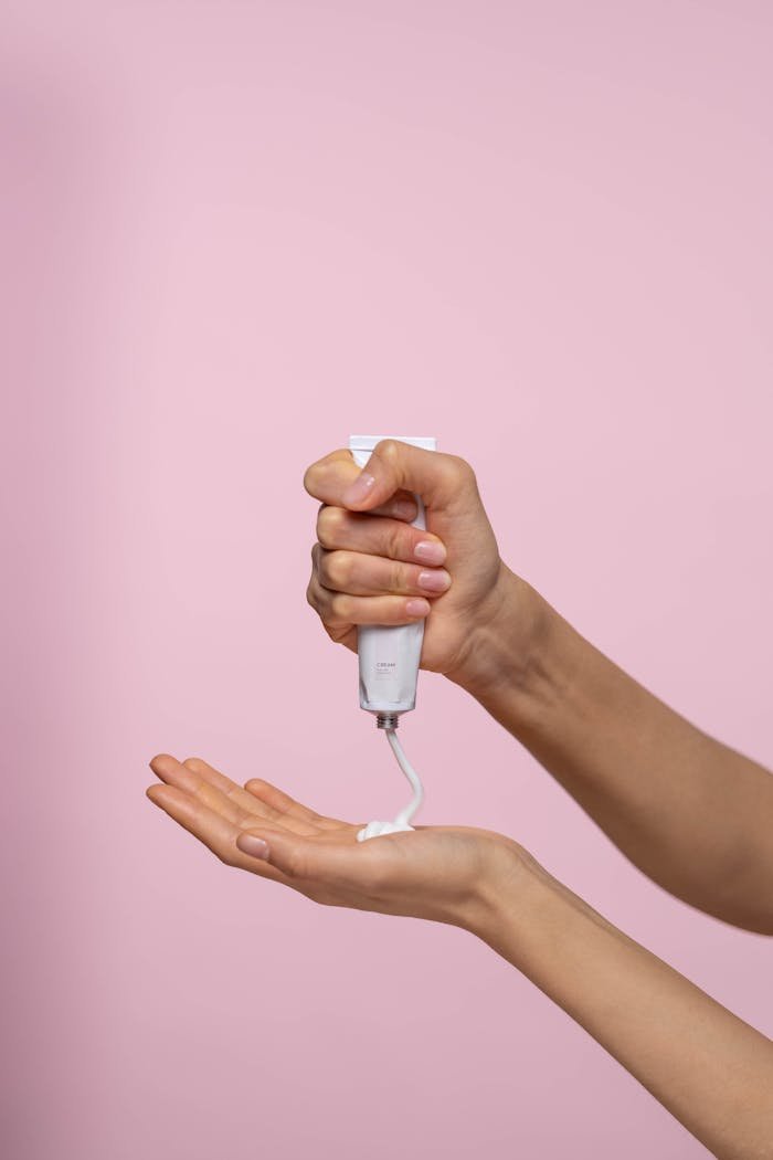 Person Holding A Cream In White Tube